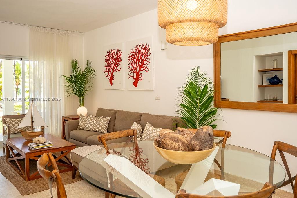 A living and dining area features a sofa, glass-topped table, and coastal-themed wall art — 000 8C3F+Q62, Las Terrenas 32000, Dominican Republic # 2, DR, DR