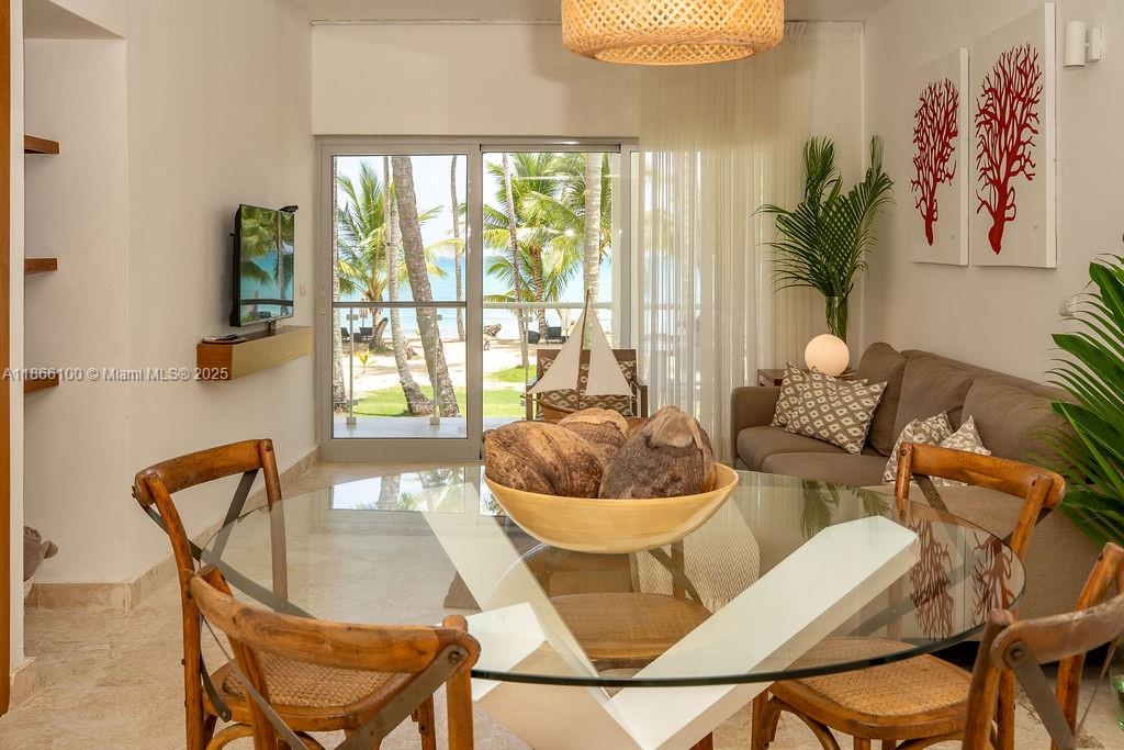 A dining area with a glass table and wooden chairs overlooks a beach through sliding doors — 000 8C3F+Q62, Las Terrenas 32000, Dominican Republic # 2, DR, DR