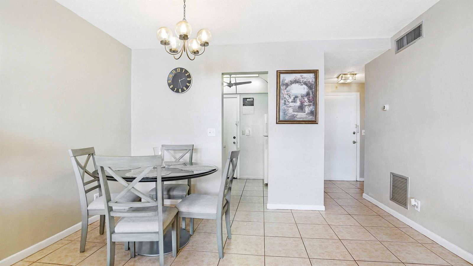 A dining area with a round table, four chairs, a chandelier, and tiled flooring — 412 S Cypress Road # 205, Pompano Beach FL 33060, POMPANO BEACH, FL