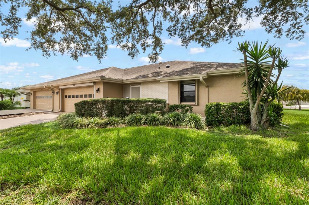 A tan single-story house with a two-car garage and a large front lawn — 1317 LELAND DRIVE, SUN CITY CENTER, FL
