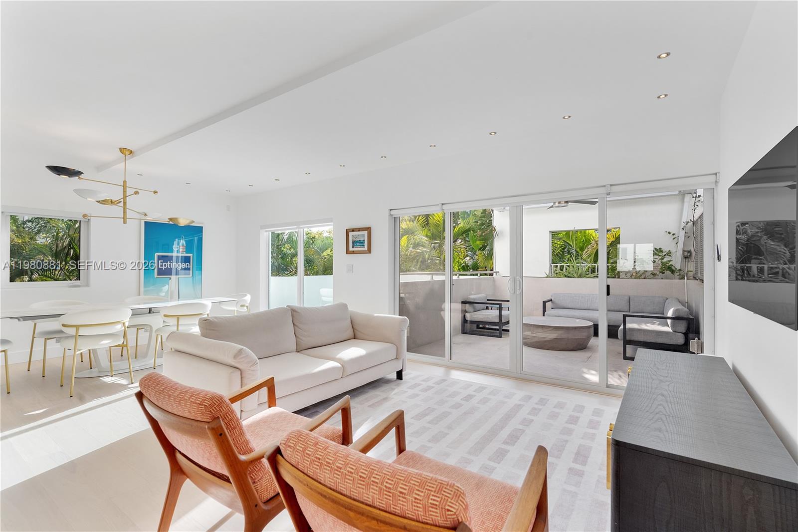 A bright living and dining area features white walls, modern furniture, and a glass-enclosed patio — 828 3rd St # 314, Miami Beach FL 33139, MIAMI BEACH, FL