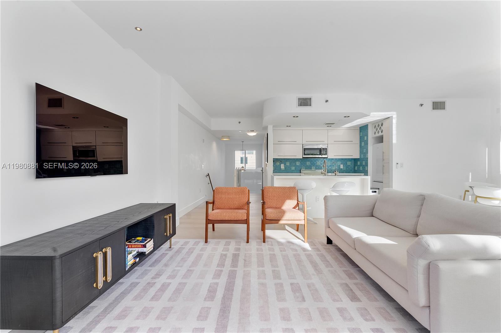A living room with a white sofa, two orange chairs, and a black media console — 828 3rd St # 314, Miami Beach FL 33139, MIAMI BEACH, FL