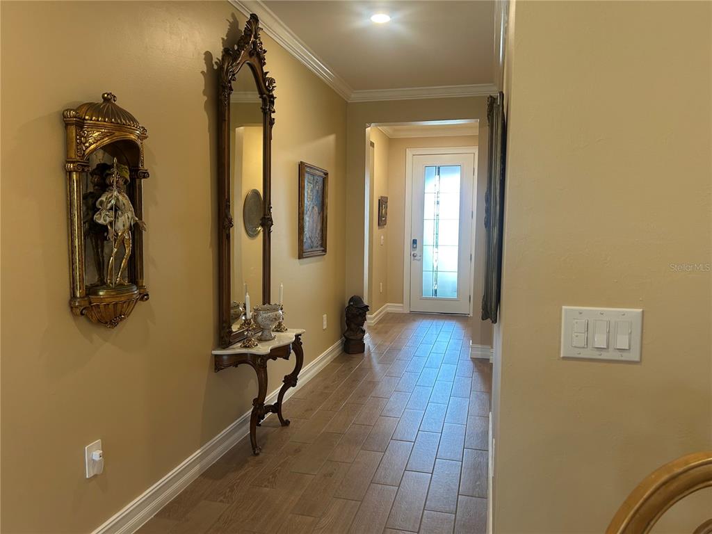 A hallway with tile flooring, a decorative mirror, a console table, and a front door — 126 VILLA PEROSA WAY, NOKOMIS, FL