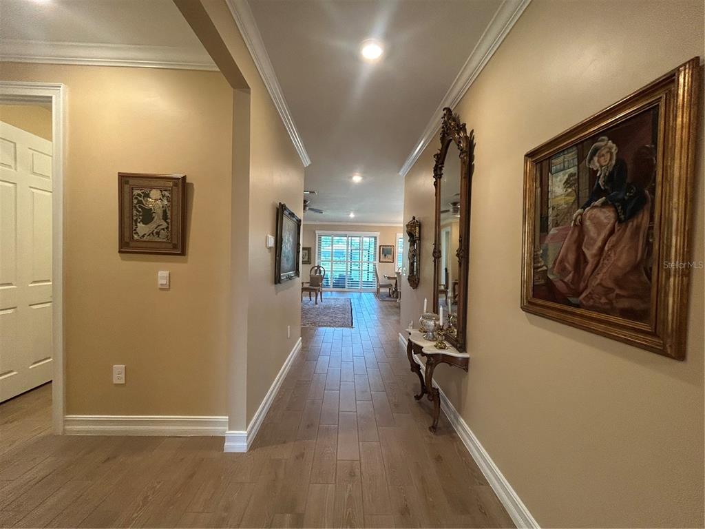 A hallway with tile flooring leads to a living area with sliding glass doors — 126 VILLA PEROSA WAY, NOKOMIS, FL