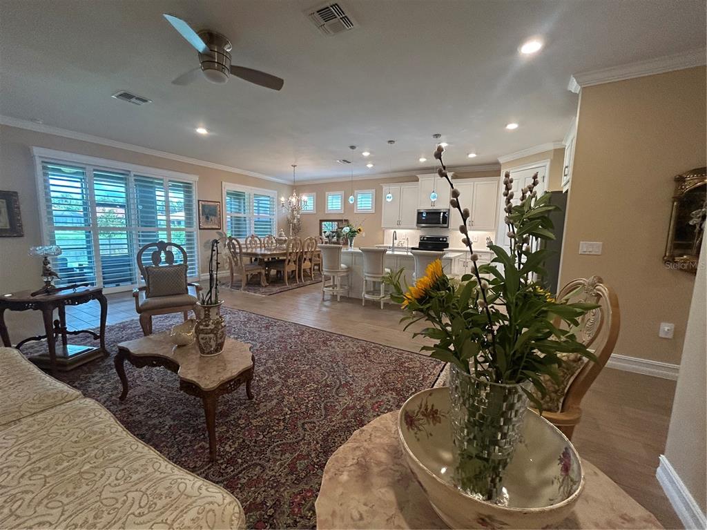 An open-concept living room and kitchen featuring a large area rug and tile flooring — 126 VILLA PEROSA WAY, NOKOMIS, FL