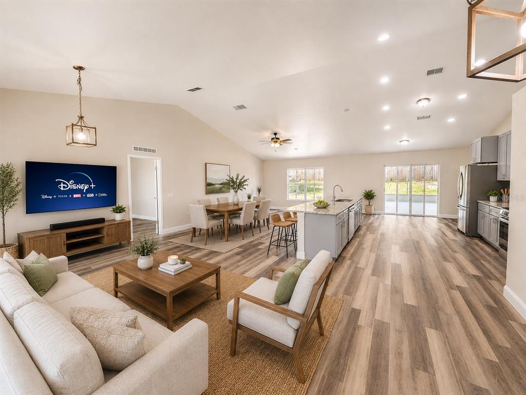 An open-concept living room and kitchen featuring light wood flooring and a vaulted ceiling — 3228 WHITE BLOSSOM LANE, CLERMONT, FL