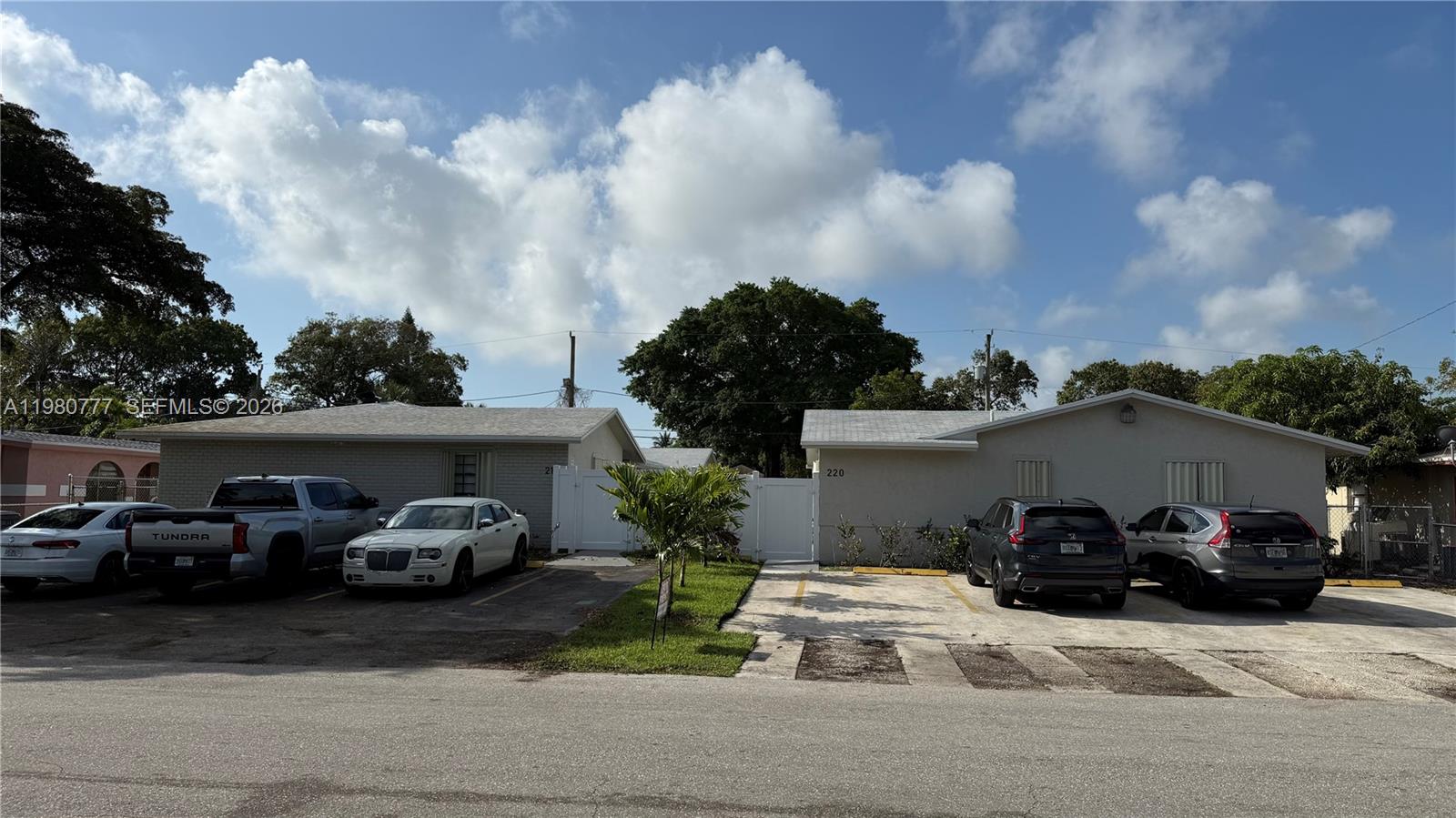 Two adjacent single-story residential buildings with parking spaces in front under a blue sky — 216 NW 12th St, Pompano Beach FL 33060, POMPANO BEACH, FL