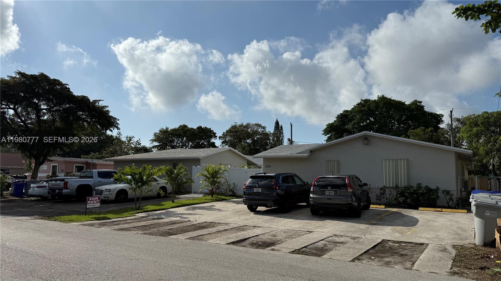 A one-story residential building with a concrete parking area and several parked cars — 216 NW 12th St, Pompano Beach FL 33060, POMPANO BEACH, FL