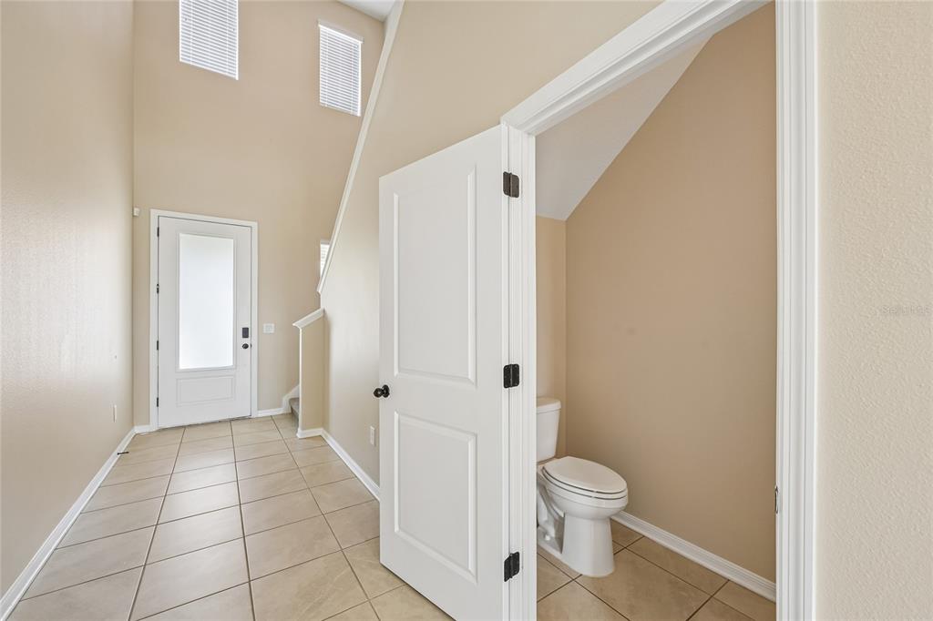 A tiled entryway features a white front door, high ceilings, and a small half bathroom — 4702 BIRDSONG DRIVE, PALMETTO, FL