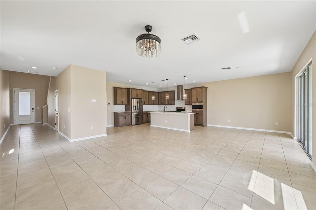 An open-concept kitchen with brown cabinetry and a central island overlooks a tiled living area — 4702 BIRDSONG DRIVE, PALMETTO, FL