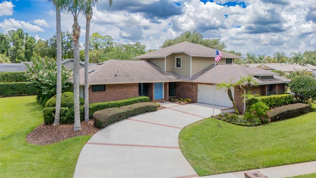 A brick and tan two-story house features a curved driveway, palm trees, and a lawn — 403 TIMBER RIDGE DRIVE, LONGWOOD, FL