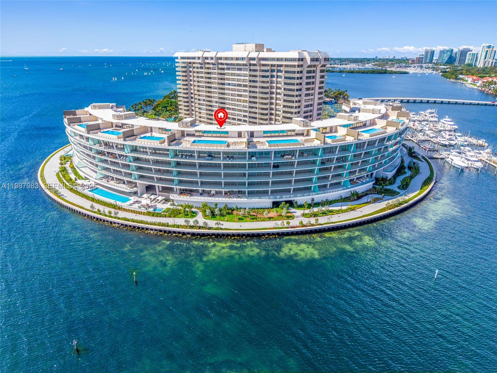 An aerial view shows a large, curved residential building complex surrounded by water — 5 Grove Isle Dr # 504, Coconut Grove FL 33133, COCONUT GROVE, FL
