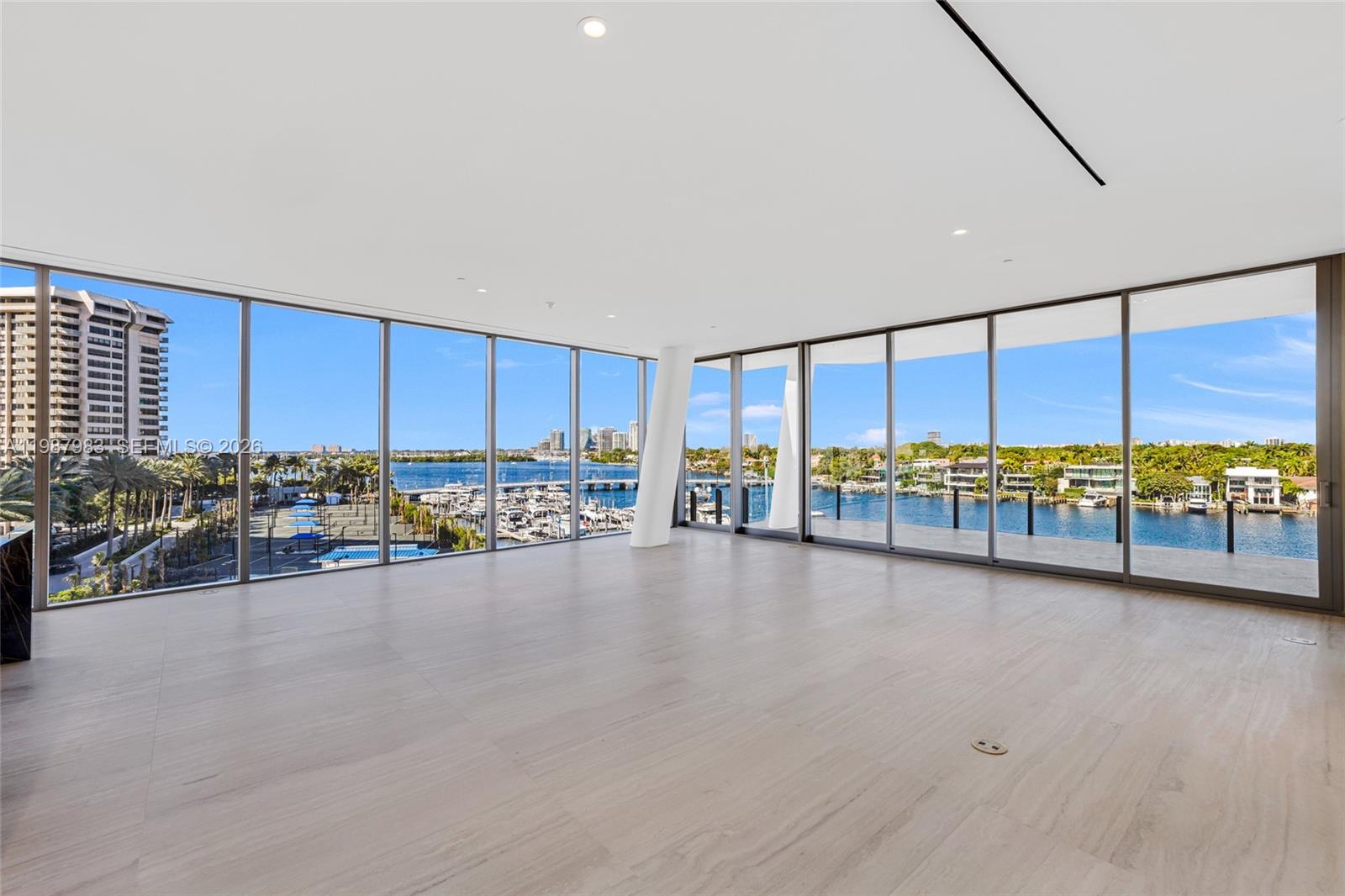 An empty room with floor-to-ceiling windows overlooking a marina and waterfront cityscape — 5 Grove Isle Dr # 504, Coconut Grove FL 33133, COCONUT GROVE, FL