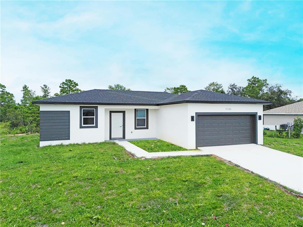 A single-story house with a white exterior, dark gray accents, and a two-car garage — 1940 ALAN STREET, SEBRING, FL