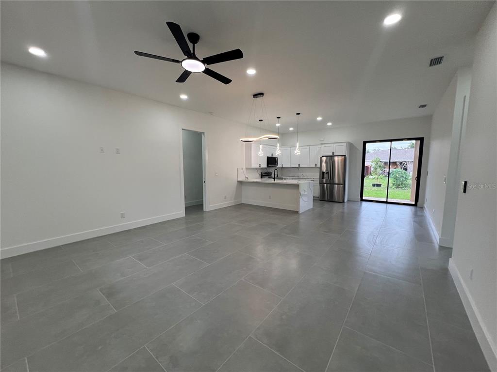 An open-concept living area features gray tile flooring, a kitchen with white cabinets, and a ceiling fan — 21492 DOLLARD AVENUE, PORT CHARLOTTE, FL
