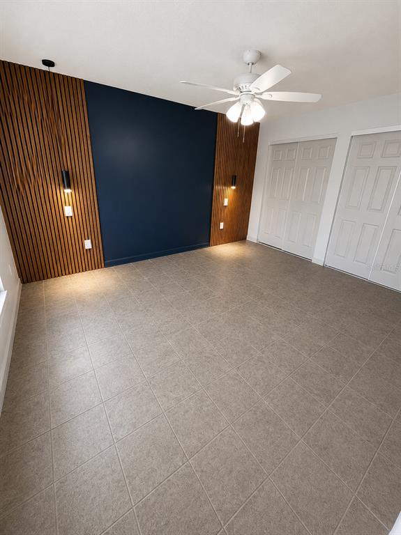 A bedroom features a dark blue accent wall flanked by wood slat panels and tile flooring — 3029-3029 WALNUT COURT, LEESBURG, FL