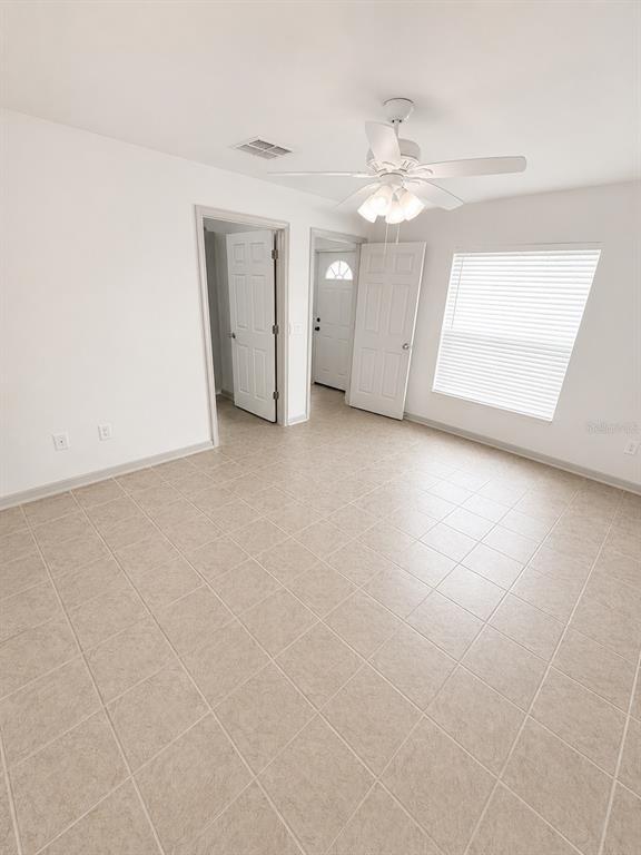 A room with light-colored tile flooring, a ceiling fan, and two white doors — 3029-3029 WALNUT COURT, LEESBURG, FL