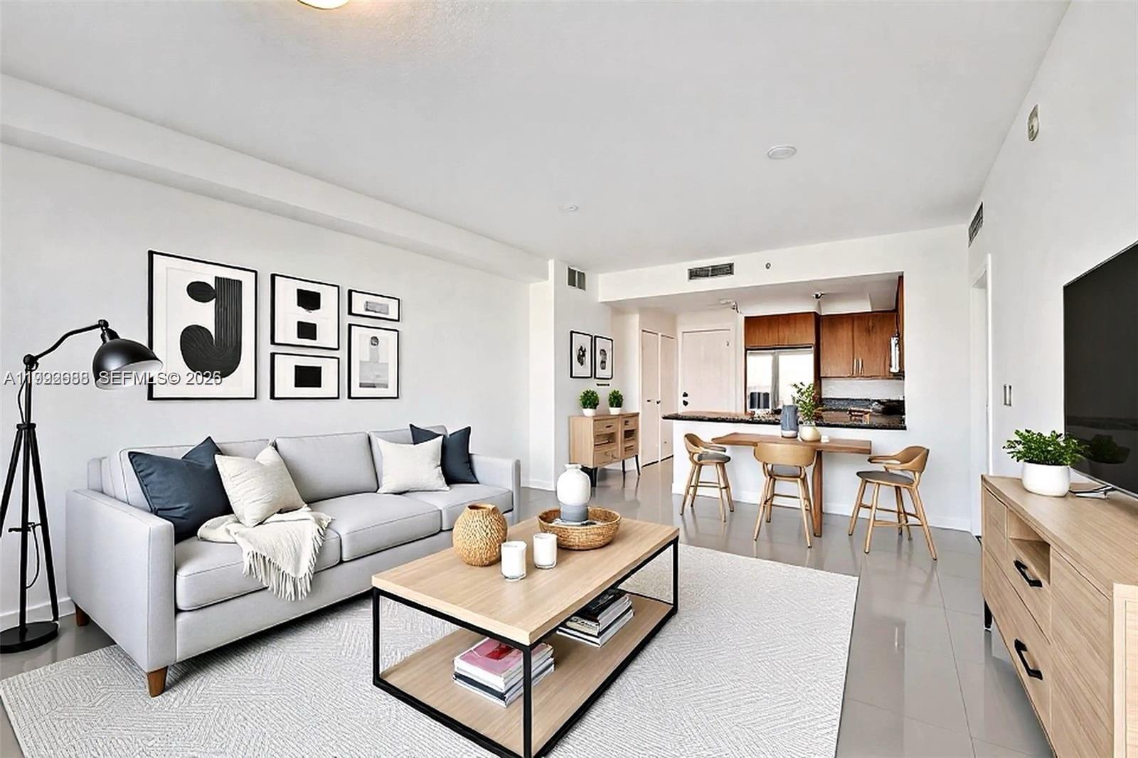 A living room with a gray sofa, coffee table, and an open kitchen with bar seating — 1830 Radius Dr # 609, Hollywood FL 33020, HOLLYWOOD, FL