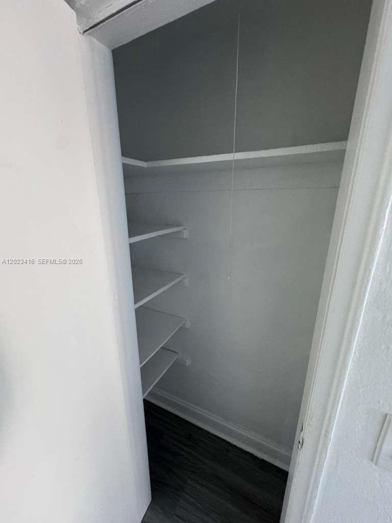 A small closet features white walls, a top shelf, and several side-mounted storage shelves — MIAMI BEACH, FL