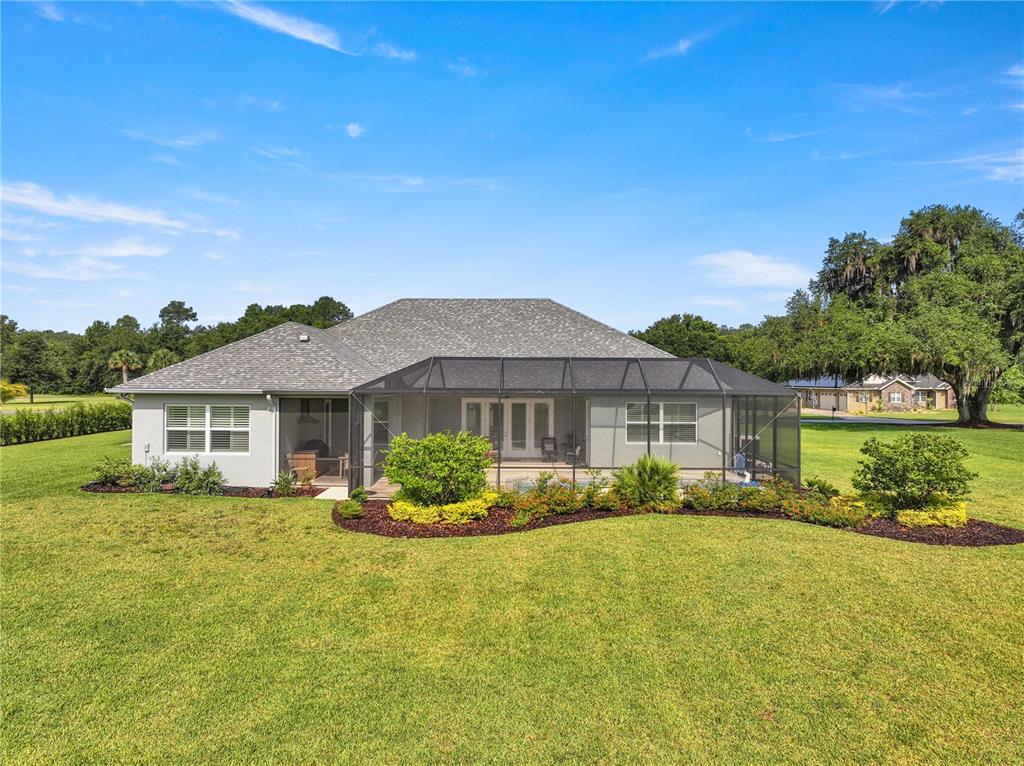 The exterior of a single-story house features a screened-in patio and a large grassy yard — 7835 SE 22ND TERRACE, OCALA, FL