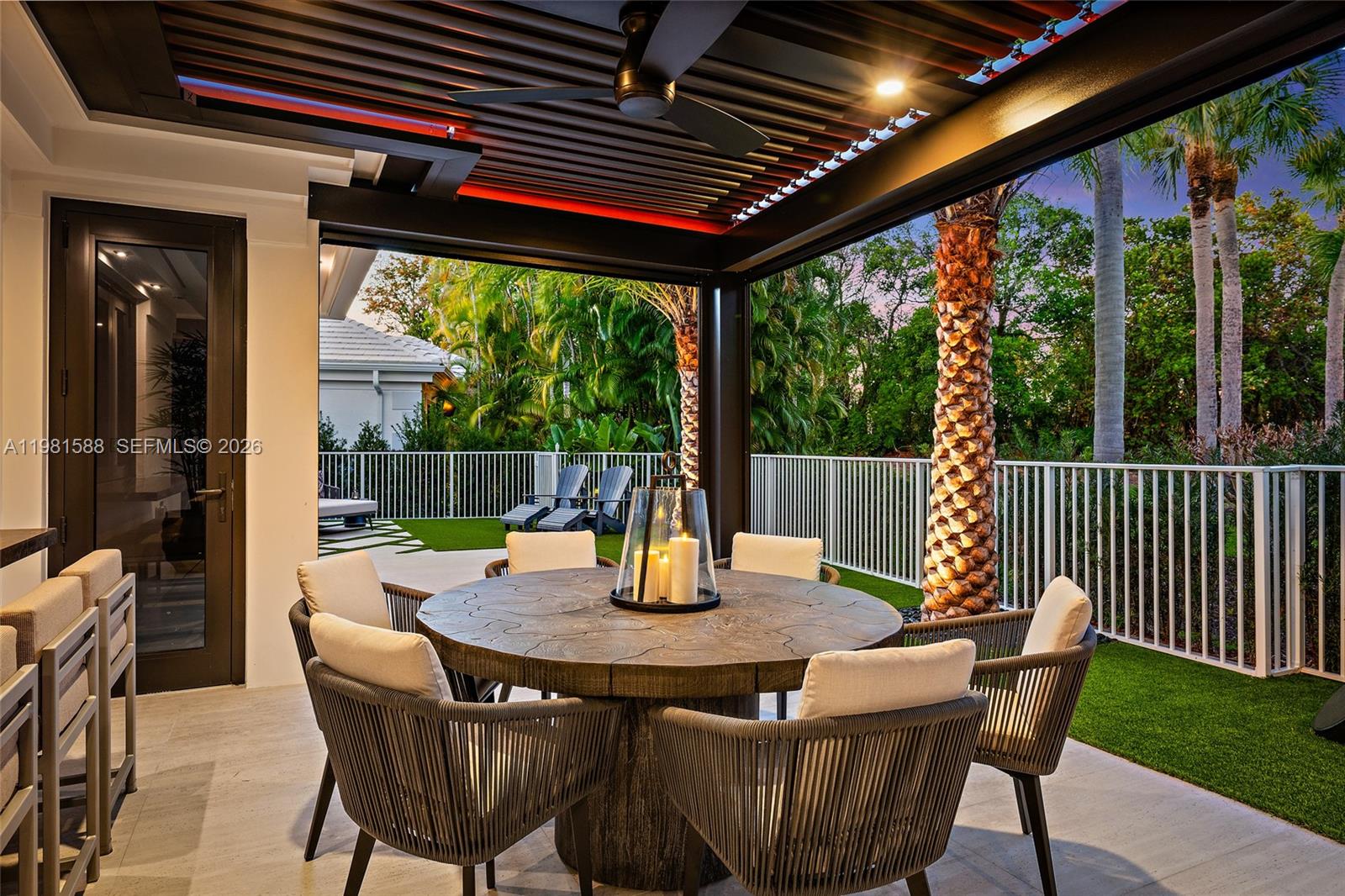 A covered outdoor patio features a round wooden dining table, chairs, and a ceiling fan — 3501 Captains Way, Jupiter FL 33477, JUPITER, FL