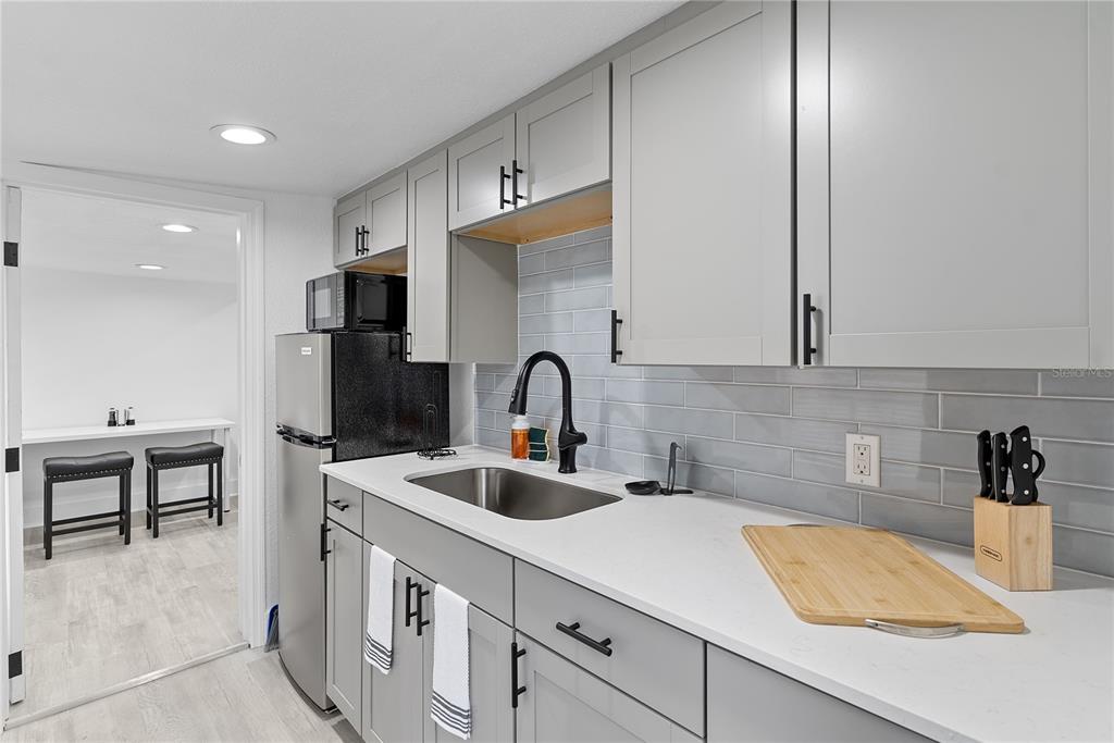 A kitchen features gray cabinets, a stainless steel sink, light countertops, and a subway tile backsplash — 412 E HARWOOD STREET UNIT 2, ORLANDO, FL