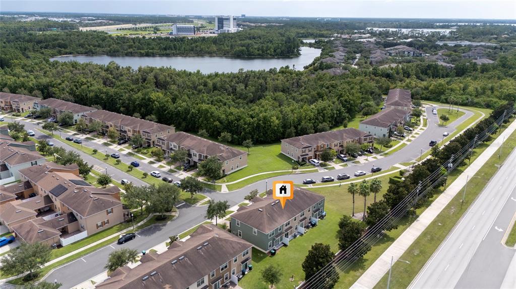 An aerial view shows a multi-unit townhouse complex with a lake and trees nearby — 10709 SAVANNAH LANDING CIRCLE, ORLANDO, FL