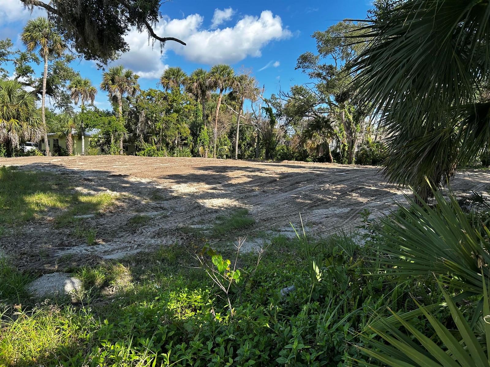 A cleared, sandy residential lot is surrounded by palm trees and lush vegetation — 525 Acacia Road, Vero Beach FL 32963, VERO BEACH, FL