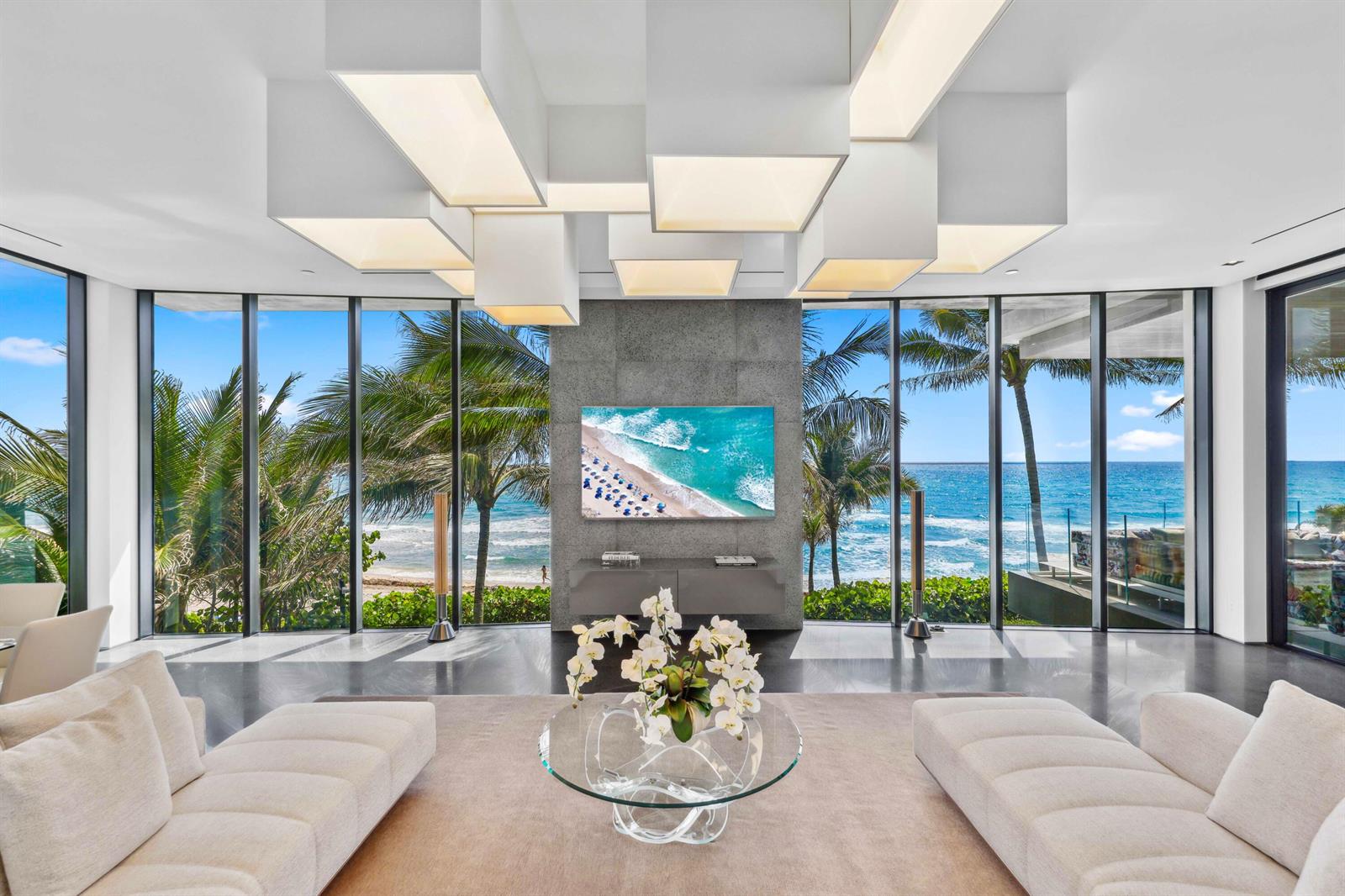 A modern living room features white box light fixtures, a stone wall, and ocean views — 3715 S Ocean Boulevard, Highland Beach FL 33487, HIGHLAND BEACH, FL