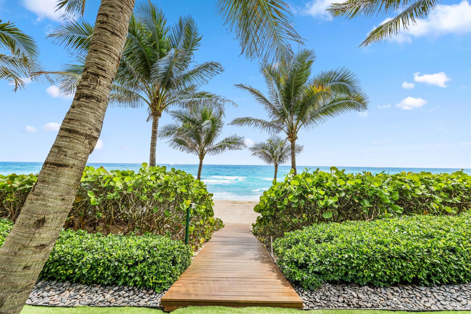 A wooden boardwalk leads through lush green landscaping toward a sandy beach and the ocean — 3715 S Ocean Boulevard, Highland Beach FL 33487, HIGHLAND BEACH, FL