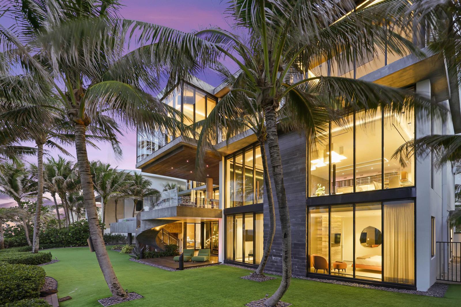 A modern multi-story house with floor-to-ceiling windows, a spiral staircase, and palm trees at dusk — 3715 S Ocean Boulevard, Highland Beach FL 33487, HIGHLAND BEACH, FL