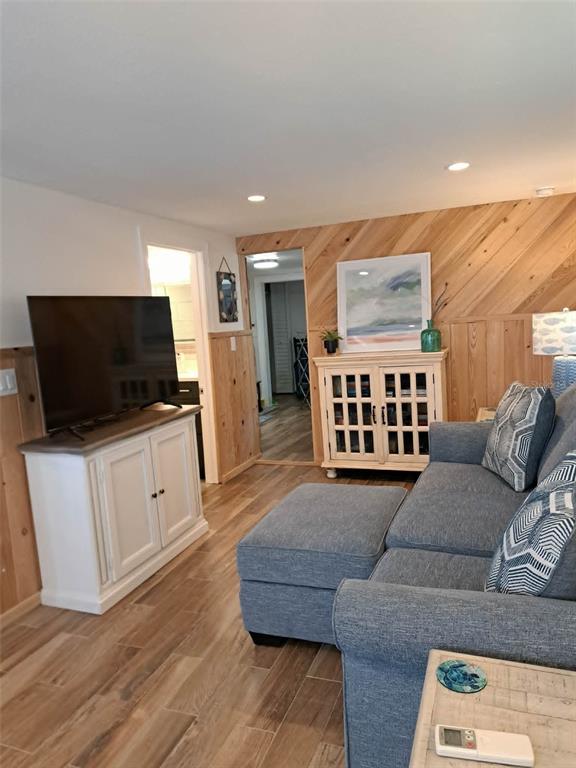A living room features wood-paneled walls, a blue sectional sofa, and a white media console — 2802 PASS A GRILLE WAY UNIT 1, ST PETERSBURG, FL