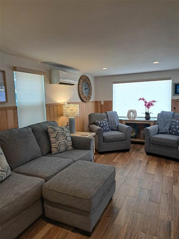 A living room features gray furniture, wood-look tile flooring, and wood wainscoting on the walls — 2802 PASS A GRILLE WAY UNIT 1, ST PETERSBURG, FL