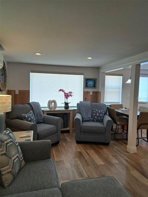 A living room features gray upholstered furniture, wood-look flooring, and windows with light-filtering shades — 2802 PASS A GRILLE WAY UNIT 1, ST PETERSBURG, FL