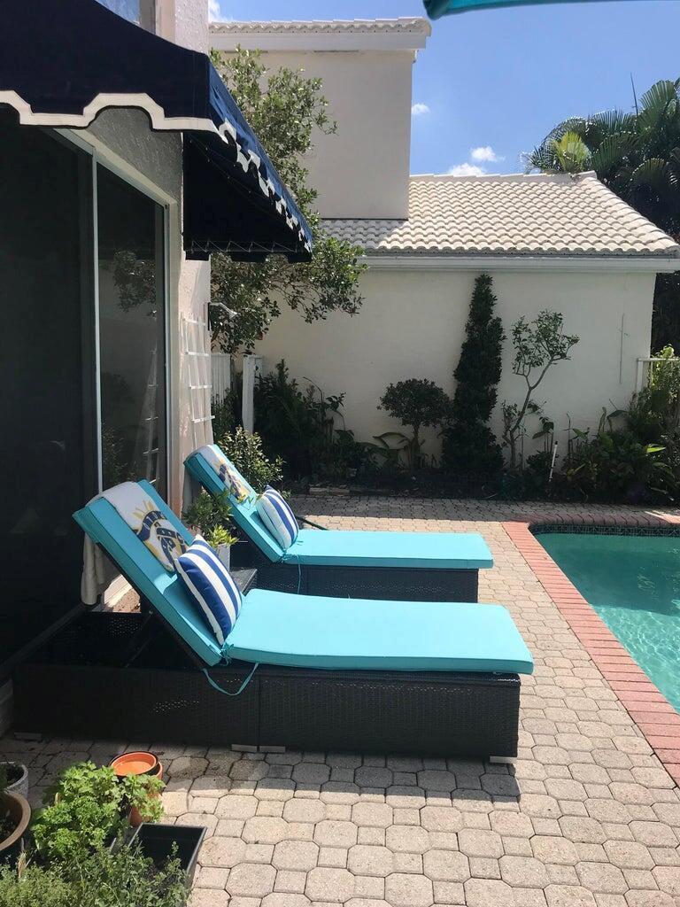 Two blue lounge chairs sit on a paved patio beside a residential swimming pool — 17275 Ventana Drive, Boca Raton FL 33487, BOCA RATON, FL