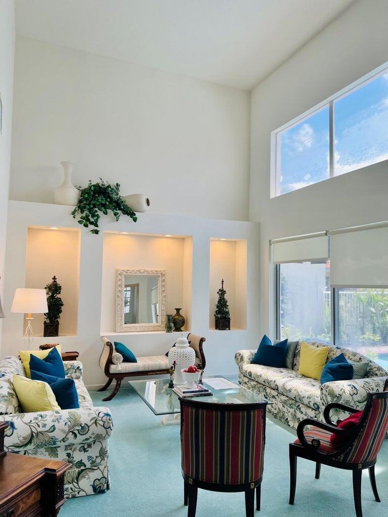 A living room features high ceilings, built-in wall niches, floral sofas, and a glass coffee table — 17275 Ventana Drive, Boca Raton FL 33487, BOCA RATON, FL
