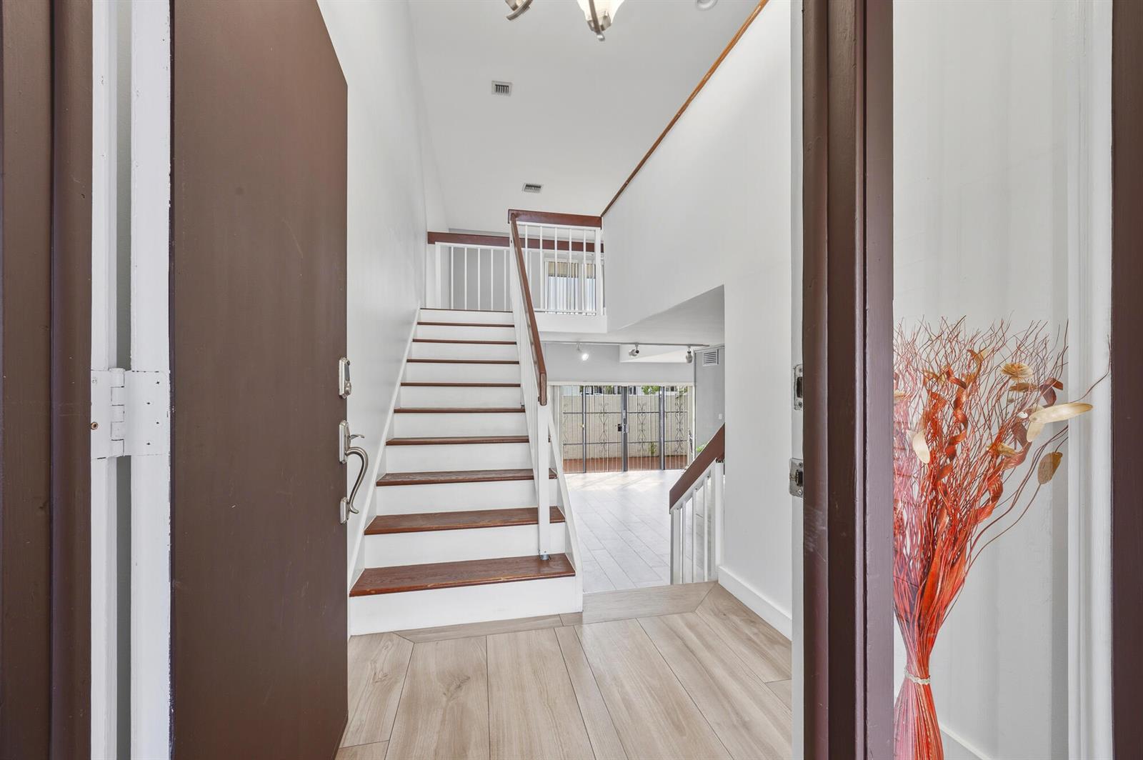An entryway features wood-look flooring, a staircase with white risers, and a view beyond — 1461 SW 124th Court # c, Miami FL 33184, MIAMI, FL
