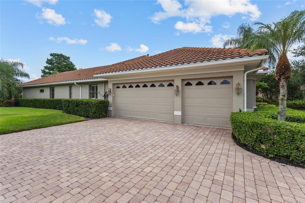 A beige house with a two-car garage and a paved driveway under a blue sky — 7808 DERBY CT, LAKEWOOD RANCH, FL