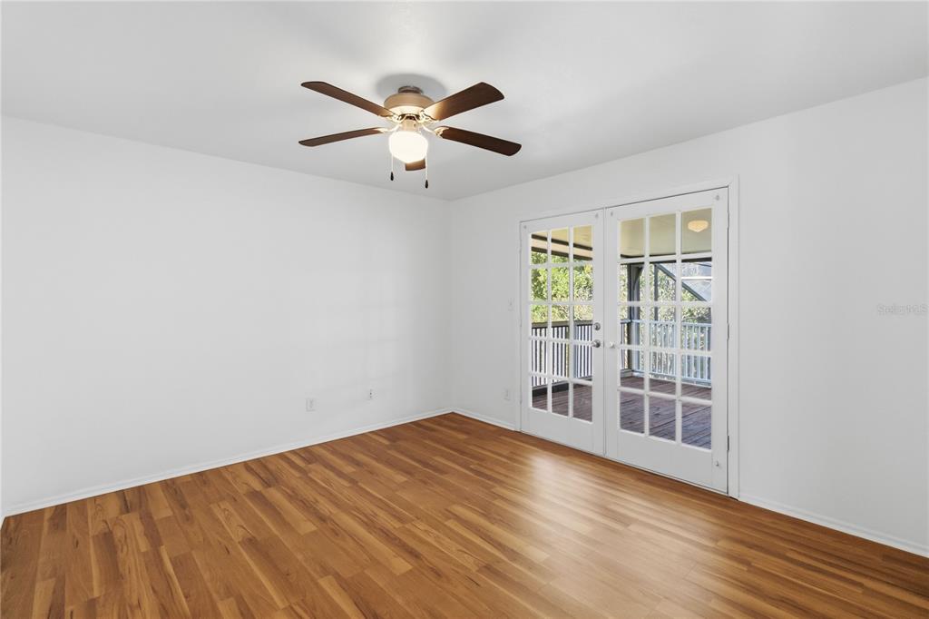 A room with white walls, wood-look flooring, a ceiling fan, and French doors leading outside — 7524 QUAIL RUN COURT, ORLANDO, FL