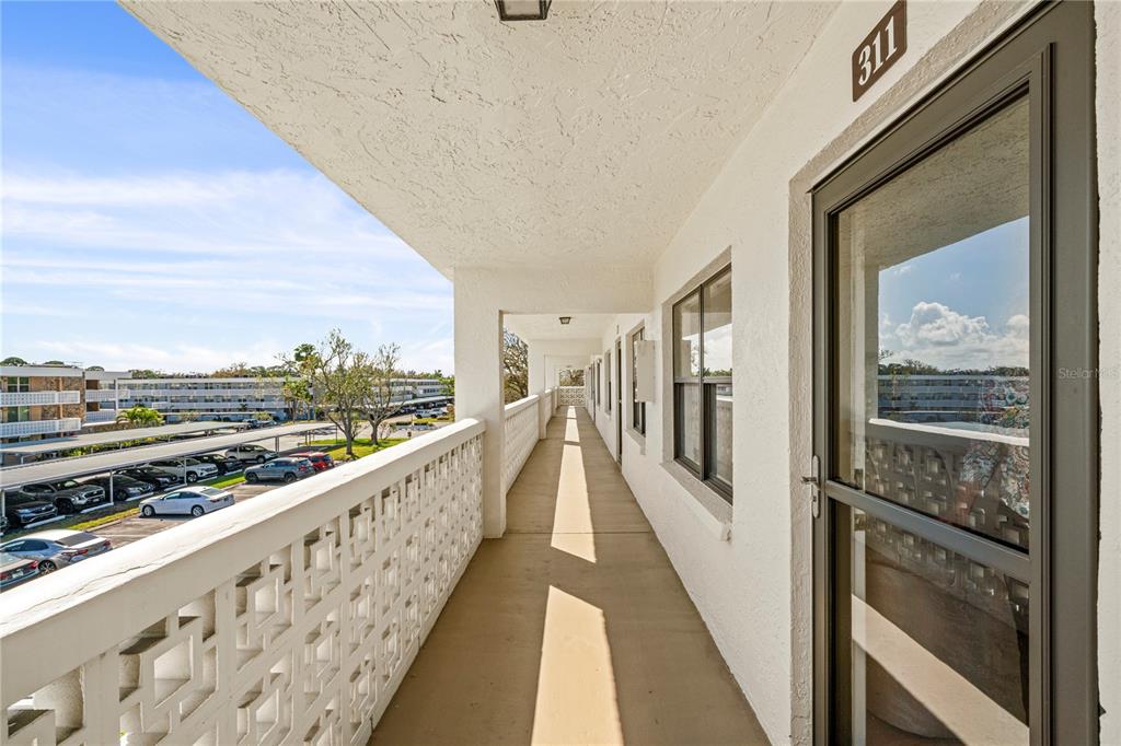 An exterior walkway with a white decorative railing overlooks a parking lot — 4910 BAY STREET NE UNIT 311, ST PETERSBURG, FL