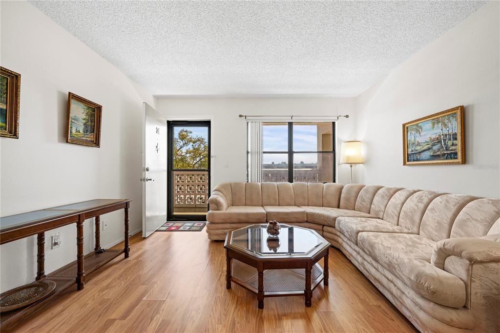 A living room features a large sectional sofa, a hexagonal coffee table, and wood flooring — 4910 BAY STREET NE UNIT 311, ST PETERSBURG, FL