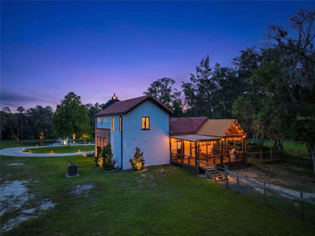 A two-story white house with a red tile roof and a covered wooden deck at dusk — 2291 WACCASSA STREET, GENEVA, FL