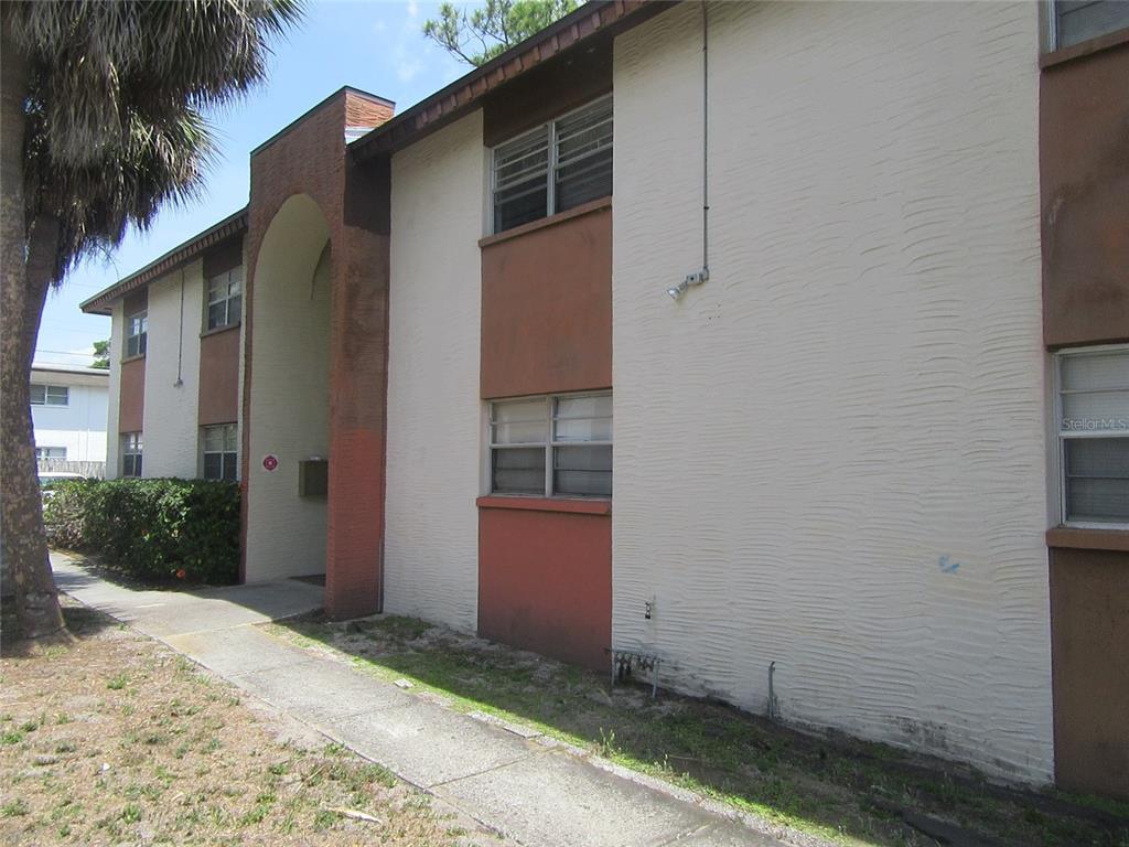 The exterior of a two-story apartment building features beige stucco walls and brown accents — 463 76TH AVENUE N UNIT 3, ST PETERSBURG, FL