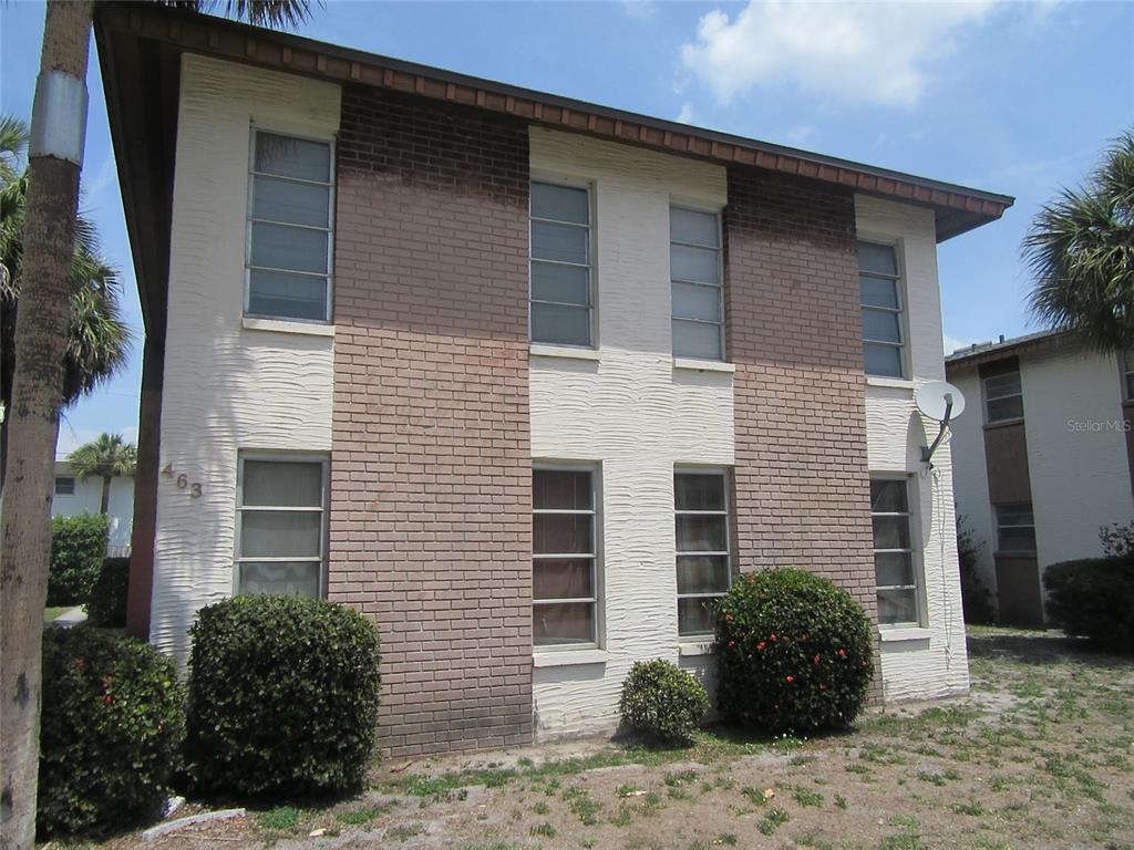 A two-story apartment building features a mix of white textured stucco and brown brick siding — 463 76TH AVENUE N UNIT 3, ST PETERSBURG, FL