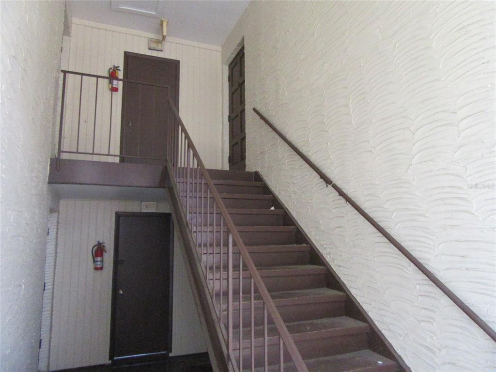 An outdoor staircase with brown railings leads to an upper landing with two dark doors — 463 76TH AVENUE N UNIT 3, ST PETERSBURG, FL