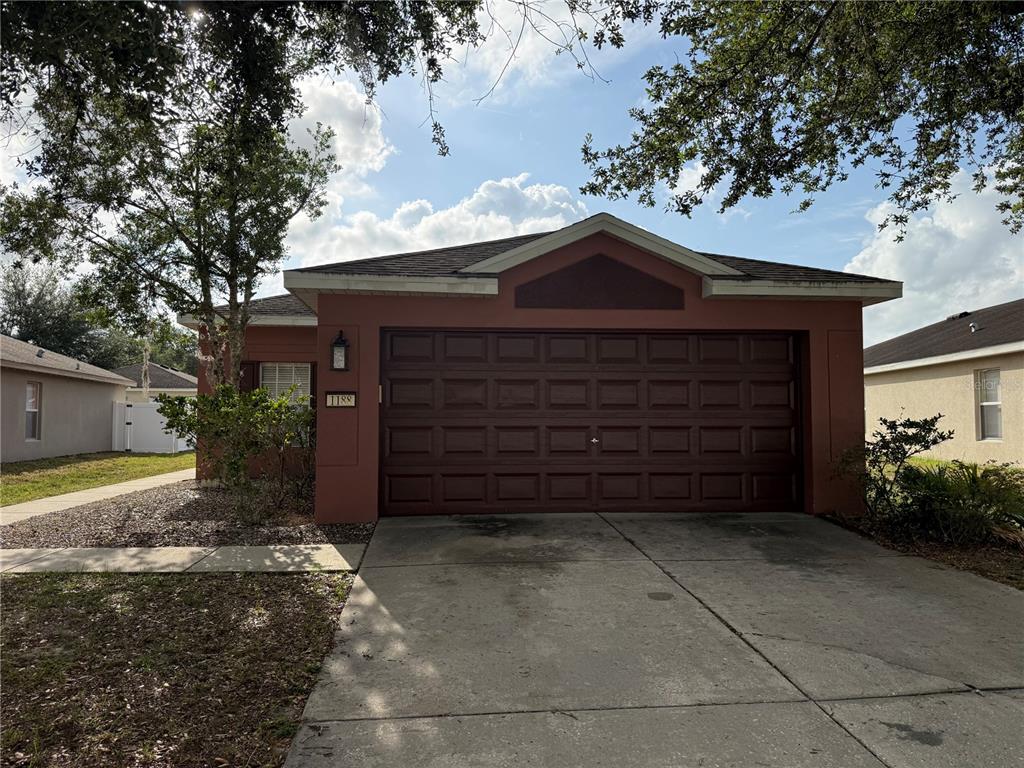 A single-story house with a brown garage door and a concrete driveway — 1188 THREE LEAF LANE, BROOKSVILLE, FL