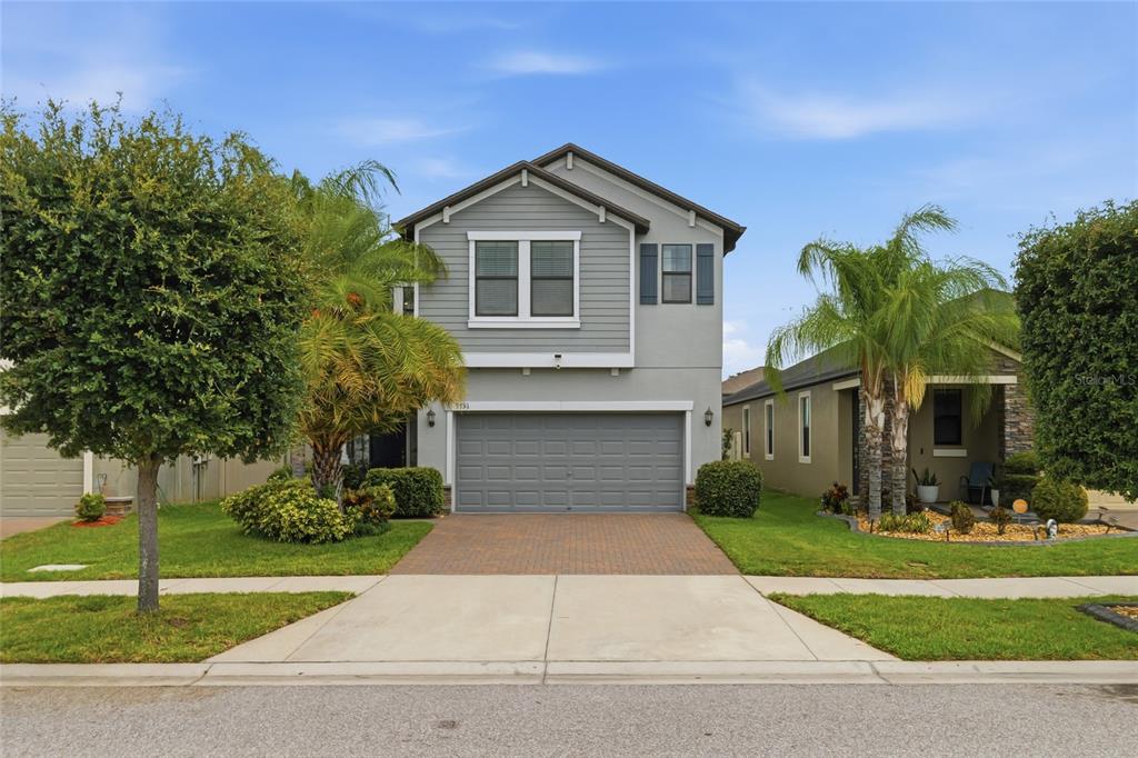 A two-story house with gray siding, a two-car garage, and a paved driveway — 9731 IVORY DR, RUSKIN, FL