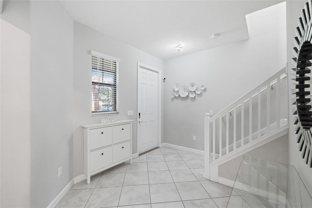 An entryway with light gray walls, white tile flooring, a white cabinet, and a staircase — 9731 IVORY DR, RUSKIN, FL