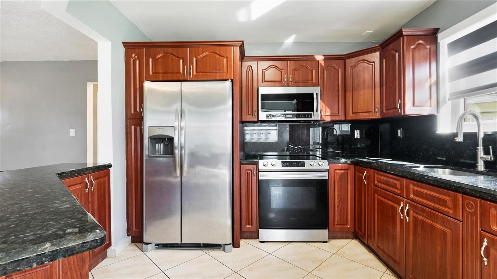 A kitchen features cherry wood cabinets, stainless steel appliances, and black granite countertops — 3140 Sheridan Lane, Hollywood FL 33021, HOLLYWOOD, FL