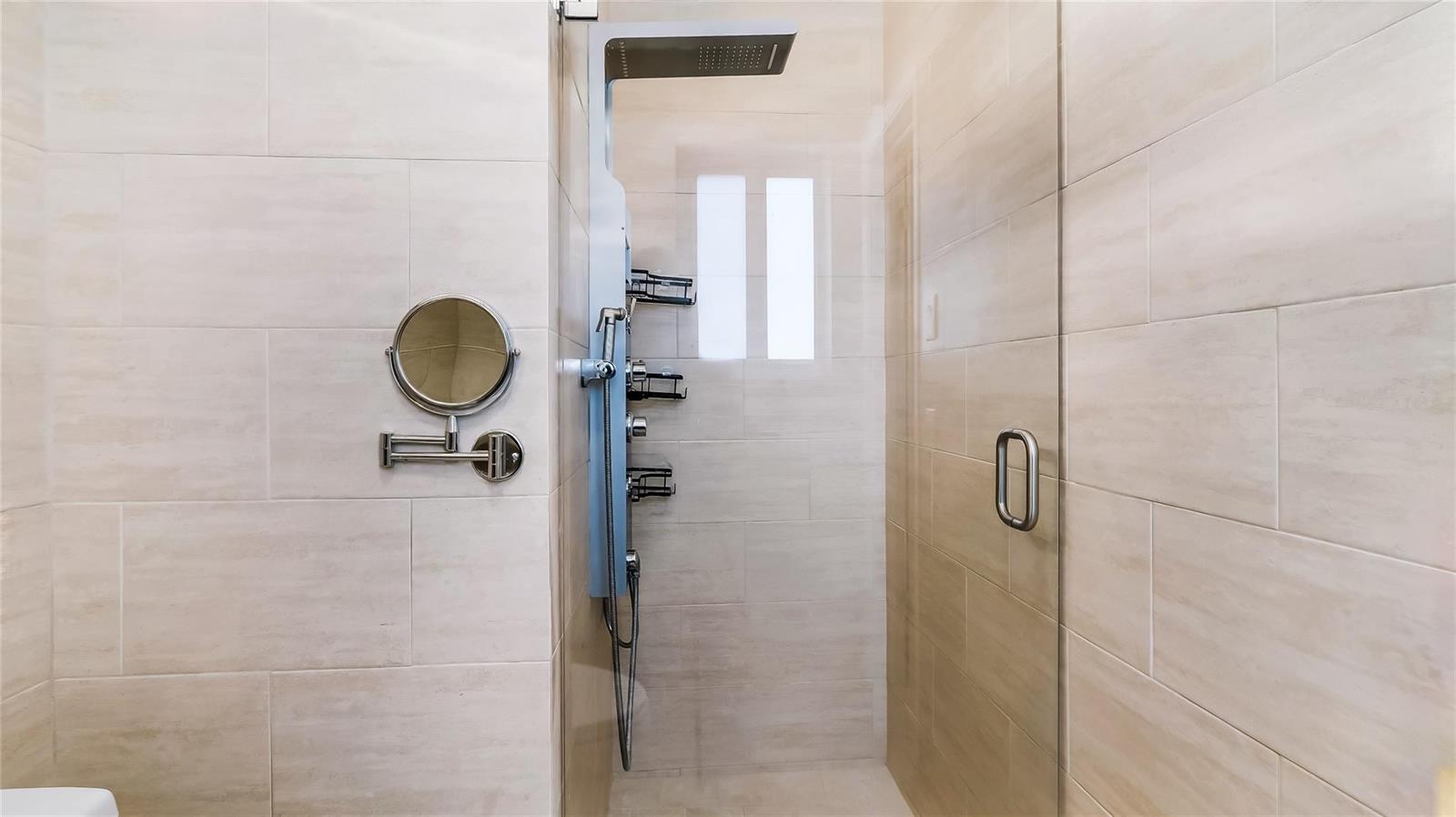 A modern shower stall features a rainfall showerhead, a handheld sprayer, and beige tiled walls — 3140 Sheridan Lane, Hollywood FL 33021, HOLLYWOOD, FL